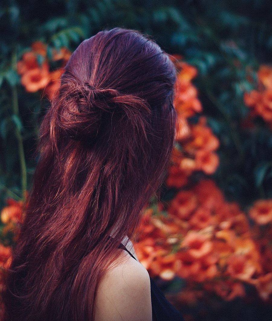 Deep red hair seen from behind against flowers